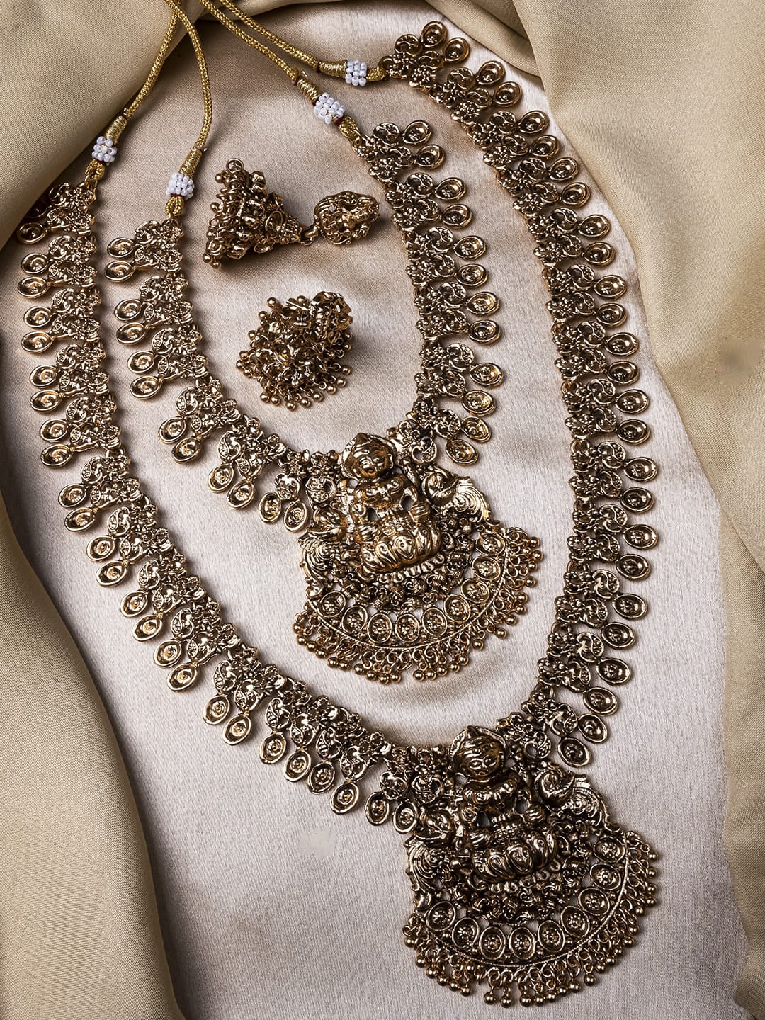 Ornate gold jewelry set on a beige fabric background