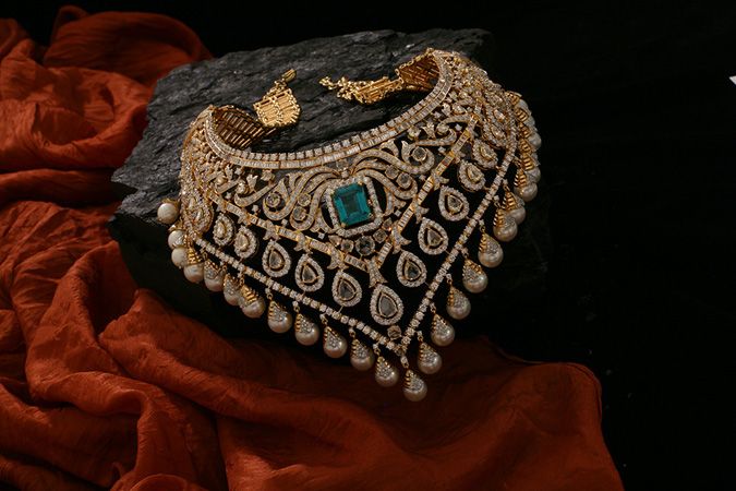 Ornate necklace with pearls and gemstones on a dark surface with red fabric