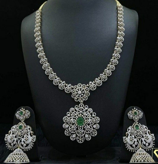 Silver necklace and earrings set on a black mannequin with green gemstones.