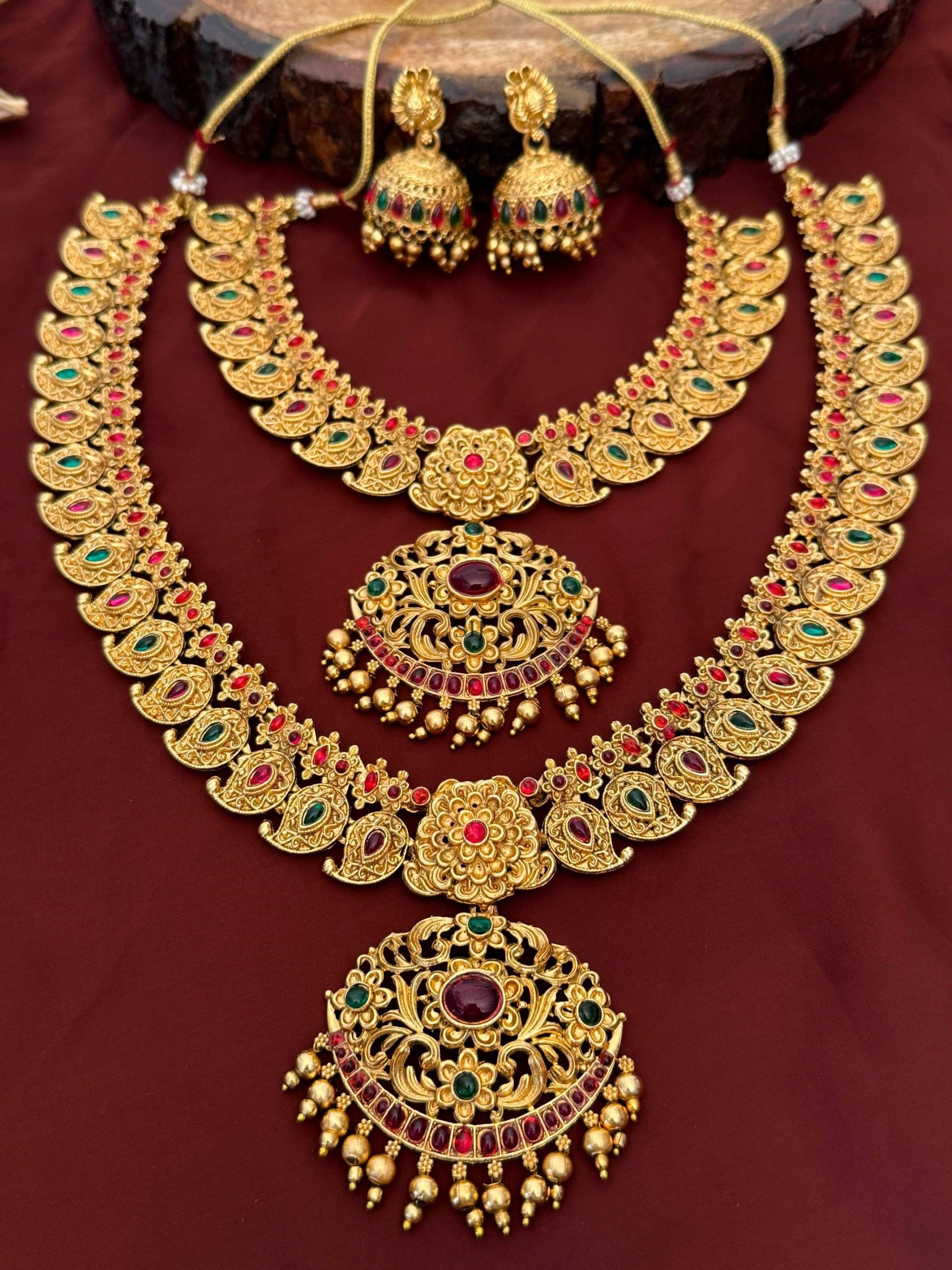 Gold necklace set with matching earrings on a dark red background