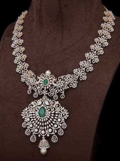 Ornate silver necklace with green gemstones on a brown fabric background